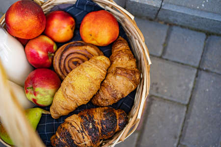 top view of a basket with fruit, apples, pears, peaches, buns and croissants. food for a picnic.の写真素材