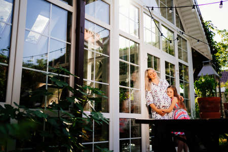 a pregnant mother and daughter are standing near a beautiful country house with large windows. happy family. vacation in the country.の写真素材