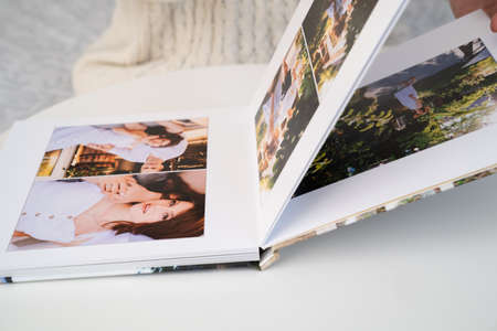 close up. a woman flips through a photo book from a family pregnancy photo shoot. beautiful and convenient storage of photos. memory of an important period.の写真素材
