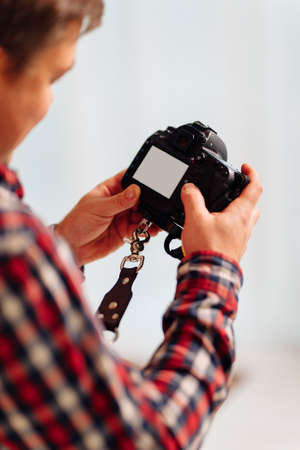 a photographer in a plaid shirt with a camera in his hands looks at the display. place for an inscription or image. creative profession. photo session in the Studio.の写真素材
