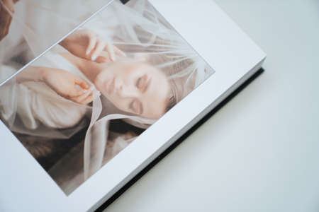 open wedding photo book. flipping through a photobook with thick pages on a white table. convenient, beautiful and long-lasting storage of photos from photo sessions.の写真素材