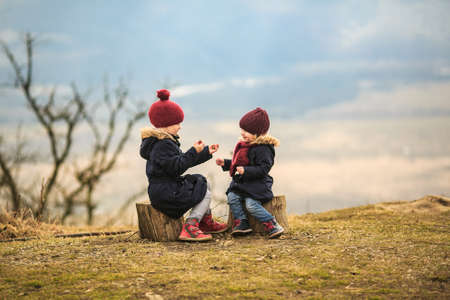 two little girls, sisters sit high in the mountains, playing palms and rock, scissors, paper. traveling with children. vacation in the winter.の写真素材