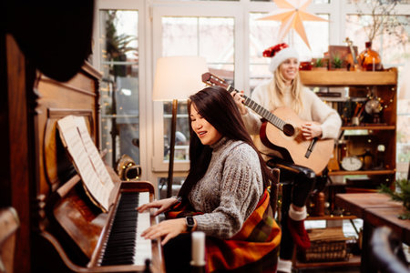 two young women play the piano and guitar in a country house.の写真素材