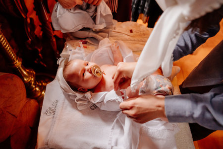 parents dress their child on a table in the Church. the ordinance of baptism.の写真素材