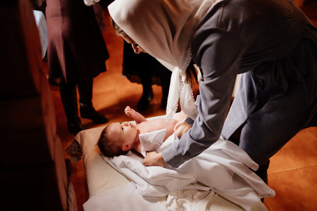 mom dress their child on a table in the Church. the ordinance of baptism.