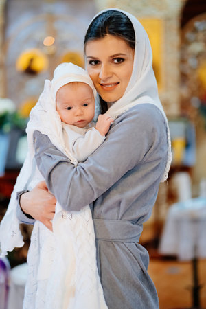beautiful mom in a headscarf with a small child in her arms in church.