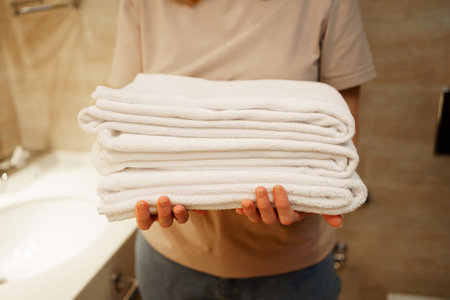 womens hands with clean white towels in hand. Replacing bath accessories.の写真素材