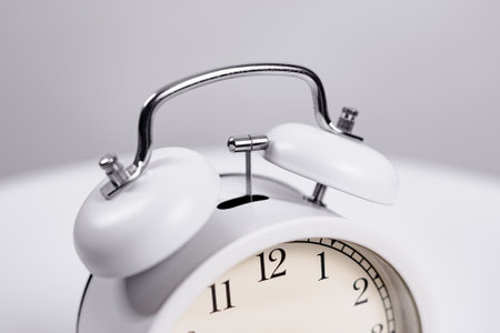 the white alarm clock is ringing. a hammer knocks on a metal bell.の写真素材