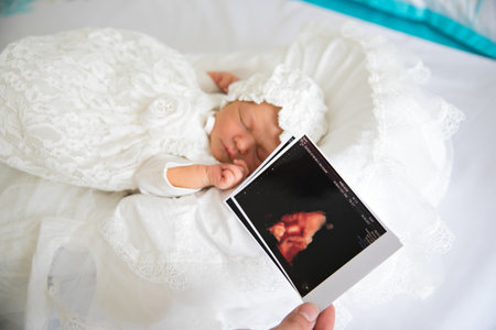 a newborn baby in white clothes and a hat is sleeping.