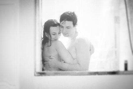 black-white. soft focus. man and woman take shower shooting through window.の写真素材
