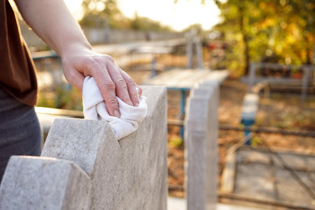 Cleaning cemetery. A womans hand washes grey monument at grave with rag.の写真素材