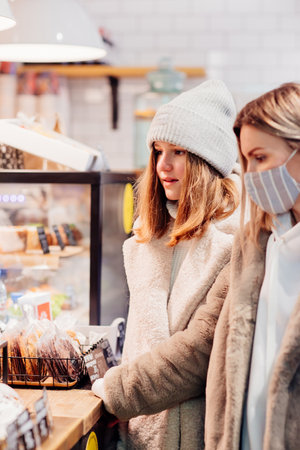 woman in protective mask makes with daughter order in cafe. contactless paymentの写真素材