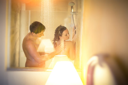 soft focus. naked man and woman take shower together in bathroom with windowの写真素材