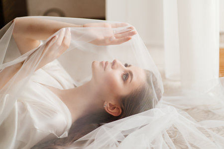 a beautiful young woman in robe is lying under a veil.の写真素材