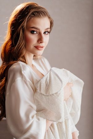 portrait of beautiful woman in white robe holding wedding dress in front of herの写真素材