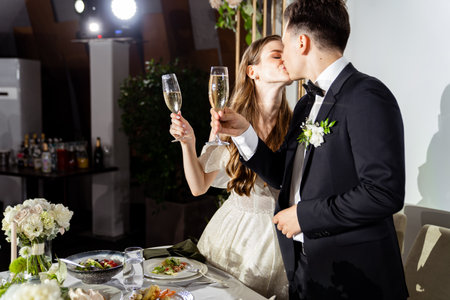 newlyweds with champagne in hands listen to toasts, congratulations and kissの写真素材