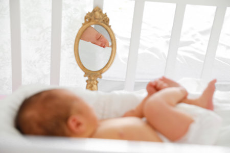 a newborn baby is lying in a crib and is reflected in a small mirror.
