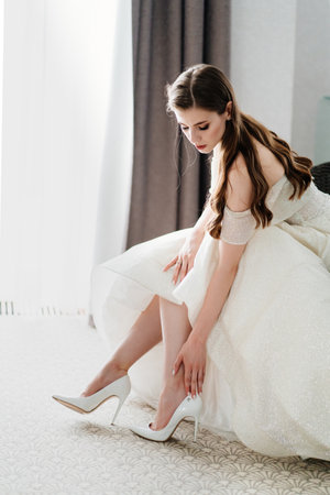 A beautiful bride puts on shoes. Preparing for the wedding ceremony.の写真素材