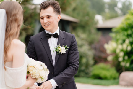 wedding ceremony in arch of living flowers. the groom listens to the brides vowの写真素材