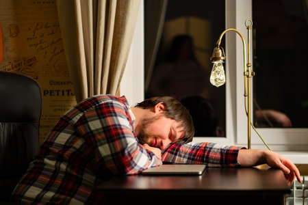 a man in red plaid pajamas worked late at the computer and fell asleep.の写真素材