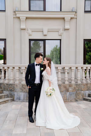 beautiful newlyweds stand against the background of a light building.の写真素材