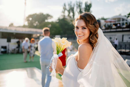 solar glare. bride with long curls in a white elegant dress with a calla lilies.の写真素材