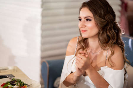 bride sit at table in restaurant and listen to congratulations from guests.の写真素材