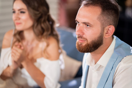 newlyweds sit at table in restaurant and listen to congratulations from guests.の写真素材