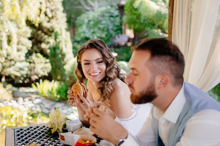 The bride and groom have fun and eat hamburgers. snack for newlyweds.の写真素材