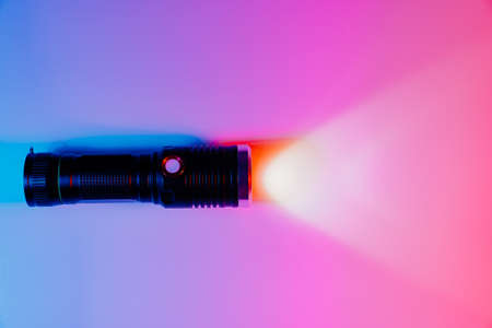 A small black flashlight in colored lighting.の写真素材