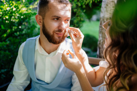 bride gently and carefully wipes the face of the groom away sweatの写真素材