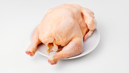 carcass of raw chicken on a white plate on a white background.の写真素材
