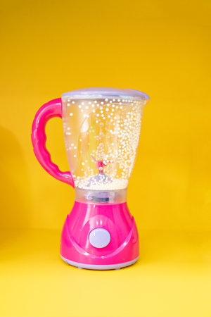 small toy pink blender on a yellow background.の写真素材