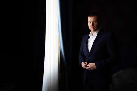 man in a jacket by the window in a dark room.の写真素材