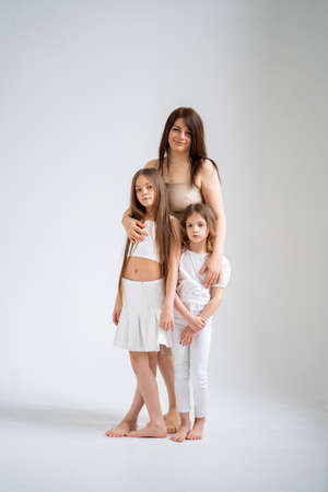 Mom and daughters pose in a white photo studio.の写真素材
