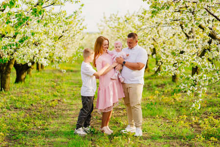family with son and daughter in spring flowering garden. cleft lip in infants.