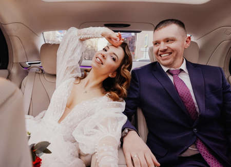 The bride and groom in the back seat of the car. Renting a car for a wedding.の写真素材
