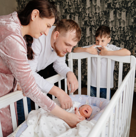 Happy family with a toddler near the childrens cradle.の写真素材