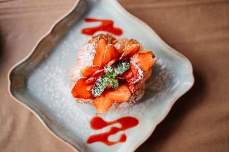 croissant with strawberries, mint and powdered sugar on a white plate.