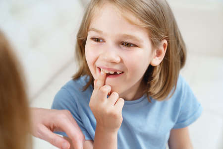 Little girl shows mother reeling tooth. changing milk teeth to indigenous teeth.