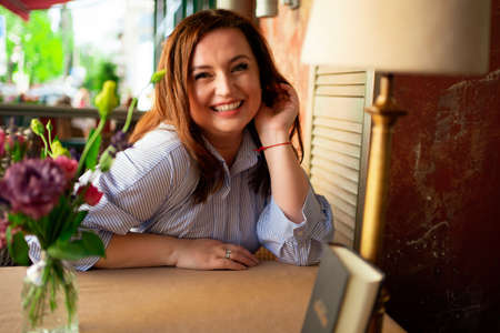 Portrait of a woman in a blue dress with long hair at a cafe table