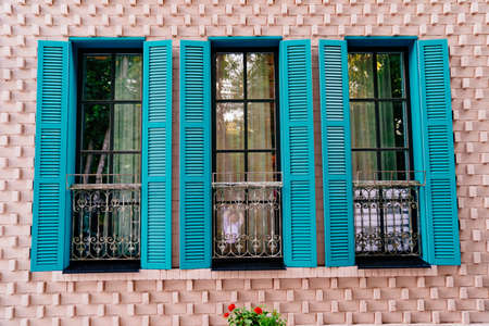 turquoise shutters on the windows of the house in retro style.の写真素材