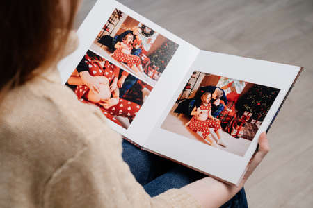 woman flips through the pages of photobook from a new years family photo shootの写真素材
