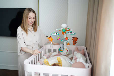 mom stands at crib of a newborn baby. furniture and toys for childrens room.の写真素材