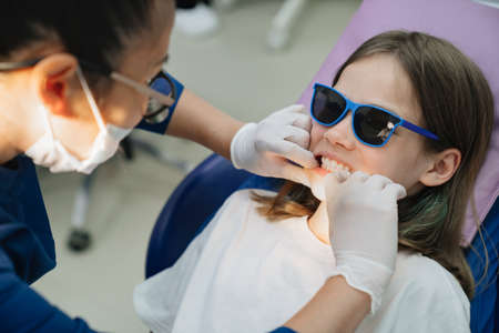 the dentist examines the mouth of a teenage girl.