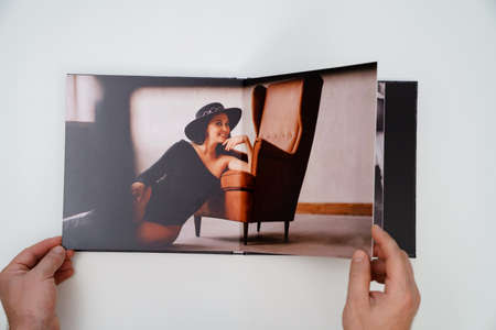 hands holding a open photobook from photo shoot of an woman on white background.の写真素材
