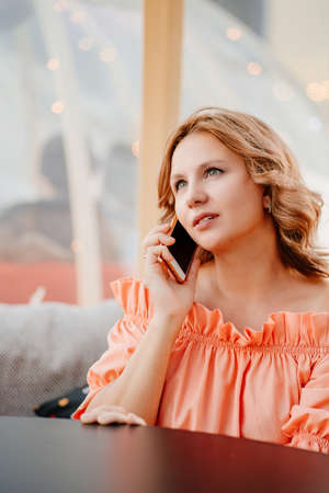 a beautiful young woman in a cafe talking on the phoneの写真素材
