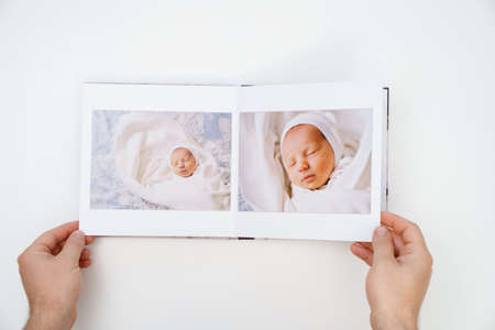 on white background, hands flip through photobook from home family photo shootの写真素材