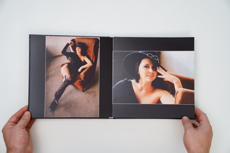 hands holding a open photobook from photo shoot of an woman on white background.の写真素材