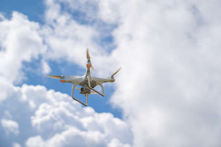 a white drone flies in the blue sky and shoots a video.の写真素材